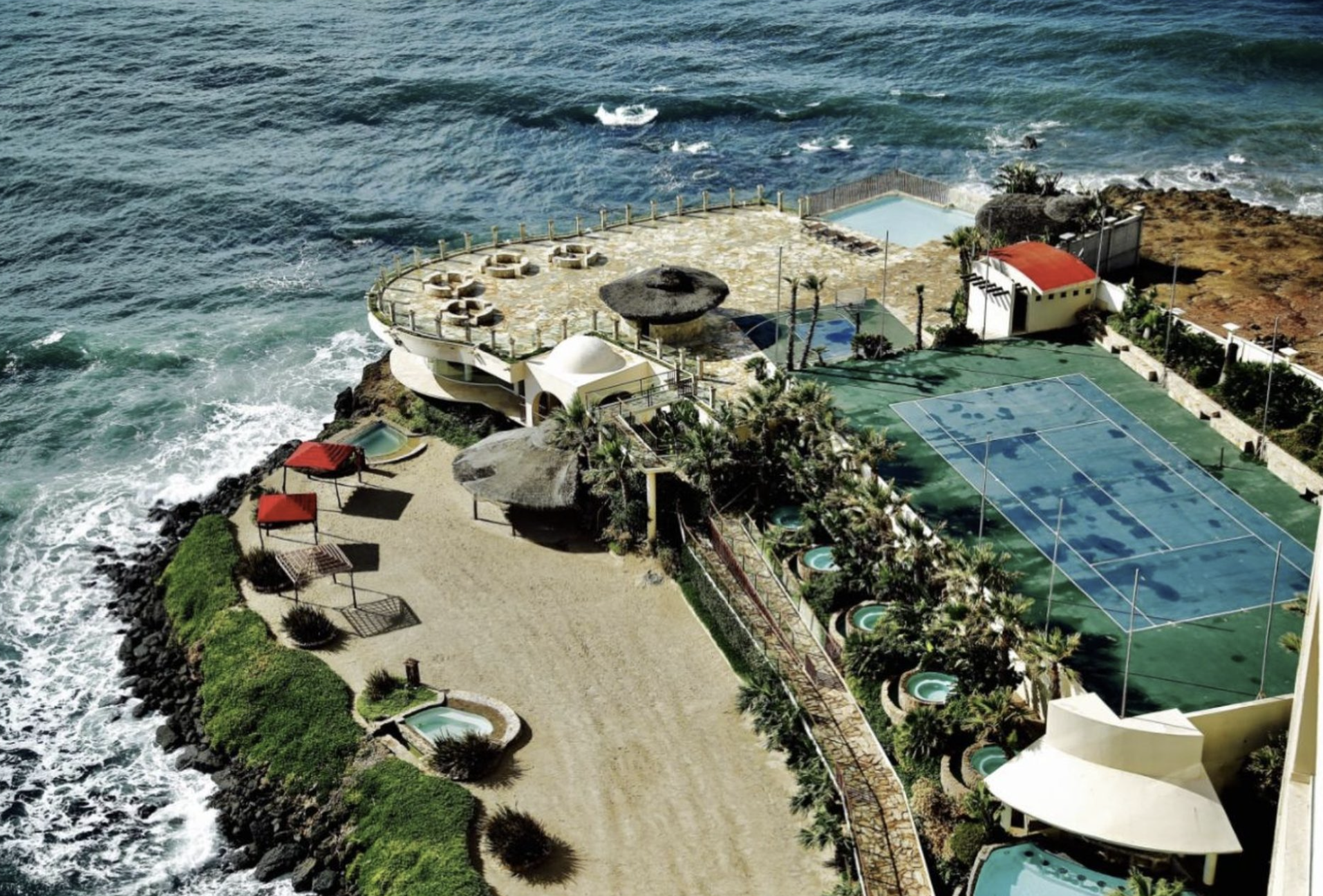 Aerial view of the oceanfront Holistic Sanctuary campus in Baja California with pools and terraces above the sea